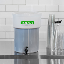 Toddy Commercial Model in cafe with coffee, plastic cups, and decanter